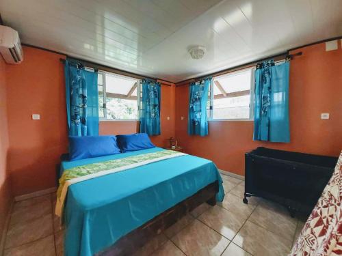 a bedroom with a blue bed and blue curtains at Studio Poe 1 Room Fare Tepua Lodge in Uturoa