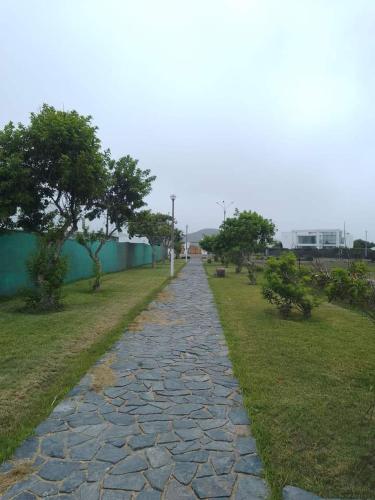 a stone walkway in a park with trees and grass at Alquilo Casa playa in San Antonio