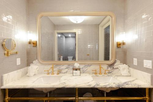 a bathroom with two sinks and a large mirror at Hotel Cleo, Knoxville Downtown, a Tribute Portfolio Hotel in Knoxville