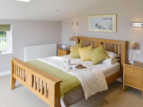 um quarto com uma grande cama de madeira com almofadas amarelas em Lock Cottage em Aylsham