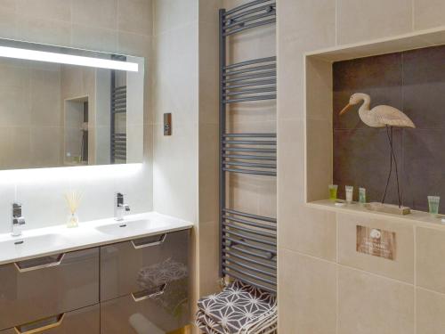 uma casa de banho com um lavatório e um chuveiro com uma estátua de um pássaro em Rook em Broadhempston