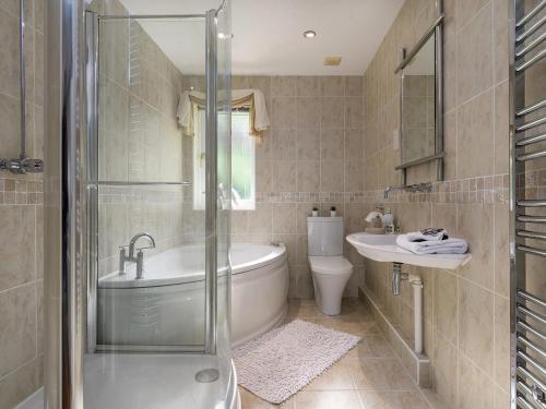 ein Badezimmer mit einer Badewanne, einem WC und einem Waschbecken in der Unterkunft Treetops in Fairbourne