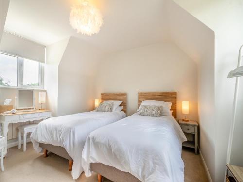 1 dormitorio con 2 camas, escritorio y lámpara de araña en The Mill Lodge, en Malmesbury