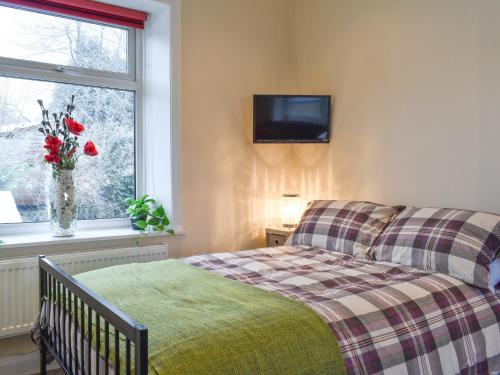 a bedroom with a bed and a window with a television at Hideaway Studio Apartment in Denby Dale