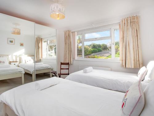 a bedroom with two beds and a window at Bay Tree in Porthscatho