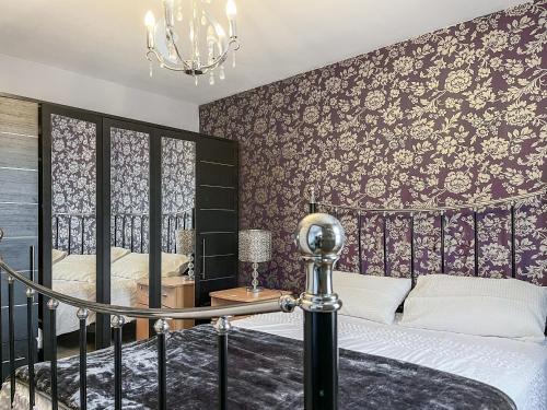 a bedroom with a bed and a wall covered in wallpaper at Royal House in Ilkeston