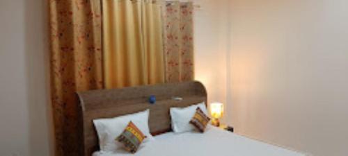 a bedroom with a white bed and a curtain at Mulberry Guesthouse Guwahati in Guwahati