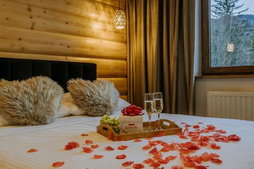 a bed with a tray of fruit and a glass of wine at Willa Zielone Wzgórze - Luksusowe apartamenty - Zakopane in Zakopane