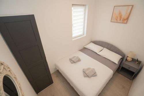 a small bedroom with a bed and a window at Apartment Danka - parking and grill in Novalja