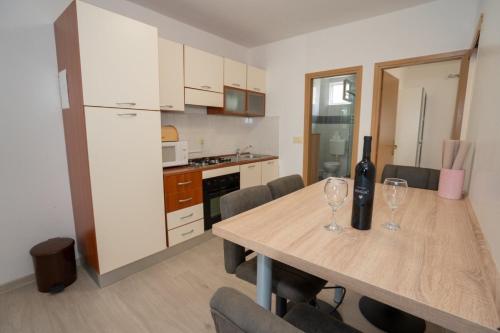 a kitchen with a wooden table with wine glasses on it at Apartment Danka - parking and grill in Novalja