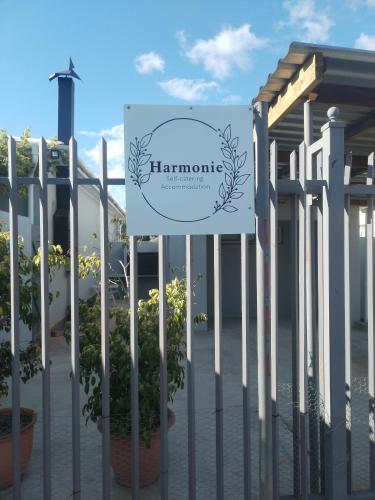 a sign on a fence with potted plants at Harmonie Self Catering in Wolseley
