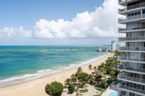 a view of the beach from the balcony of a building at Esperanza Beach 2BDR 2B Oceanfront Pool Parking in San Juan