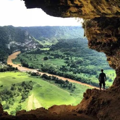a man standing at the top of a cliff looking out from a cave at Esperanza Beach 2BDR 2B Oceanfront Pool Parking in San Juan