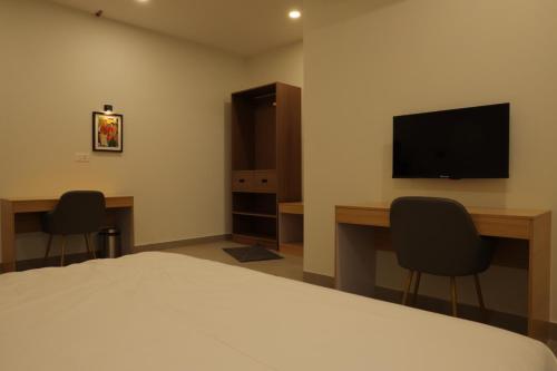 a bedroom with a bed and a desk and a television at Dreamotel Luxury Suites in Kanjikode