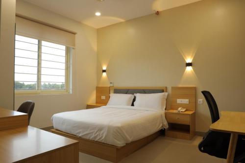 Habitación de hotel con cama, escritorio y mesa. en Dreamotel Luxury Suites, en Kanjikode