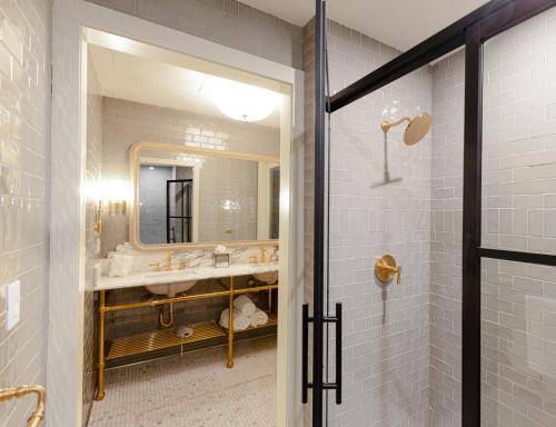 a bathroom with a shower and a sink and a mirror at Hotel Cleo, Knoxville Downtown, a Tribute Portfolio Hotel in Knoxville
