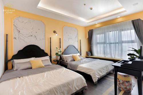 two beds in a room with yellow walls at FLC Sea Tower Condotel in Quy Nhon