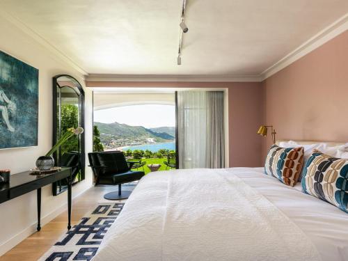 a bedroom with a bed and a desk and a window at Villa Coste Simons Town in Simonʼs Town
