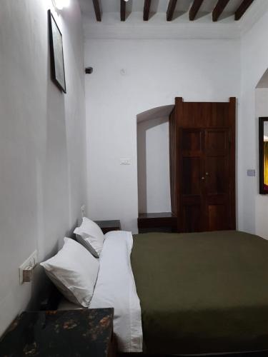 a bedroom with a bed and a wooden cabinet at Heritage Home, Hampe's in Mysore