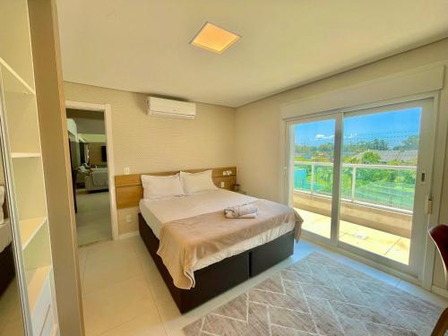 ein Schlafzimmer mit einem Bett und einem großen Fenster in der Unterkunft Atlântida Green Square - 408B in Xangri-lá