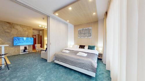 a hotel room with a bed and a tv at Grand Apartments Hrebienok in Smokovce