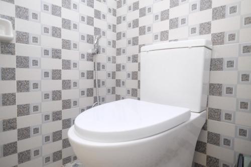 a white toilet in a bathroom with tiled walls at RedDoorz Syariah near Gerbang Dieng 2 in Dieng