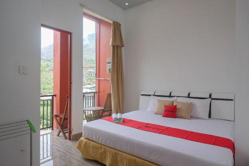 a bedroom with a large white bed and a balcony at RedDoorz Syariah near Gerbang Dieng 2 in Dieng