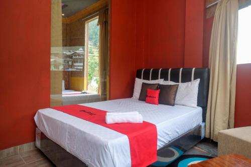 a bedroom with a bed with red walls and a window at RedDoorz Syariah near Gerbang Dieng 2 in Dieng