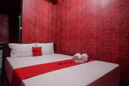 a room with a bed with a red brick wall at RedDoorz Syariah near Gerbang Dieng 2 in Dieng