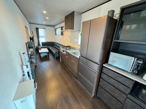 a small kitchen with a refrigerator and a sink at 温泉付き貸別荘 風車村 E-10 with hot spring in Takashima