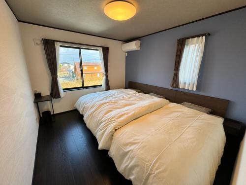 sypialnia z dużym łóżkiem i oknem w obiekcie 温泉付き貸別荘 風車村 E-10 with hot spring w mieście Takashima
