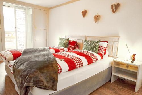 a bed with red and white blankets and pillows at Sweet Room by Interlaken in Därligen