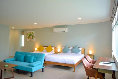 a bedroom with two beds and a blue couch at Le Divine Comedie Beach Resort in Baan Tai