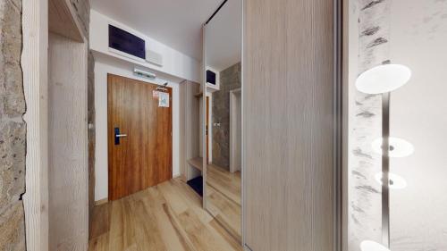 a hallway with a wooden door and a mirror at Grand Apartments Hrebienok in Smokovce