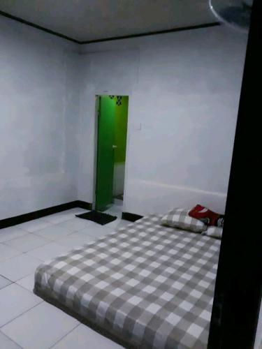 a bedroom with a bed in a room with a green door at Penginapan & Homestay Geopark Ciletuh in Cikadal