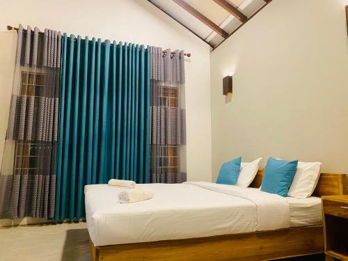 sypialnia z łóżkiem i niebieską zasłoną w obiekcie Oceano Beach Villa w mieście Arugam Bay