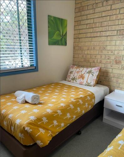 1 dormitorio con 1 cama con pared de ladrillo en Coolum Budget Accommodation, en Coolum Beach