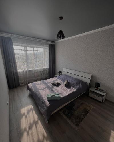 Schlafzimmer mit einem Bett und einem Fenster in der Unterkunft Квартира в центре города , ЖК Наследие in Kökschetau
