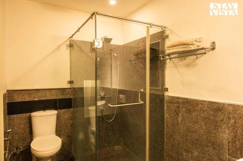 een badkamer met een glazen douche en een toilet bij StayVista's Casba Farm Retreat - Pet-Friendly Villa with Rooftop Lounge, Outdoor Pool, Lawn & Bar in Chandīgarh