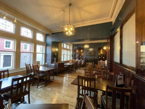 The Station Hotel Penrith في بنريث: غرفة طعام مع طاولات وكراسي ونوافذ