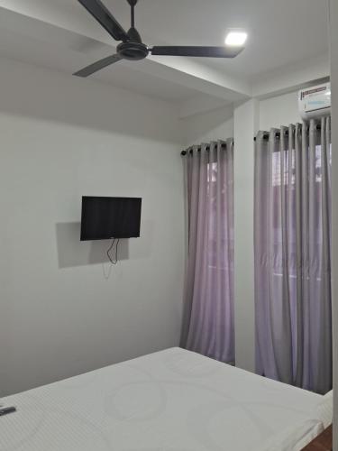 a bedroom with a ceiling fan and purple curtains at RKO Villa27 - Unawatuna in Habaraduwa