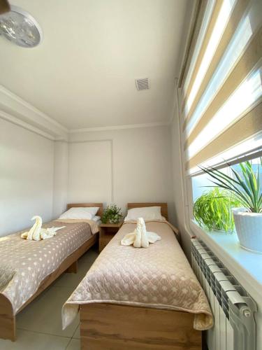 two beds in a room with a window at Sayak hostel in Karakol