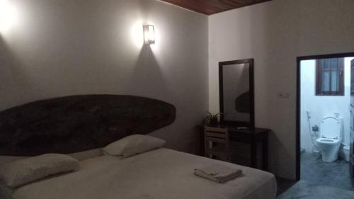a bedroom with a bed and a toilet and a mirror at Arugambay PodBay in Arugam Bay