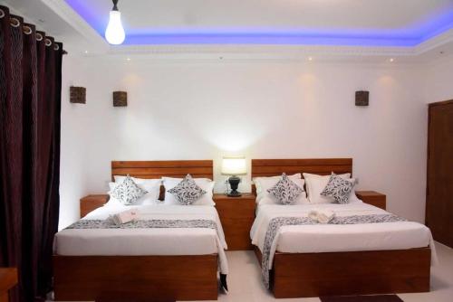 sypialnia z 2 łóżkami i niebieskim sufitem w obiekcie blooming hotel w mieście Anuradhapura