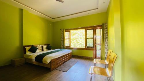 a bedroom with green walls and a bed and a window at Fishing owl Home Stay in Kālādhūngi