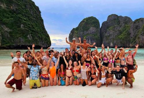 a group of people posing on the beach at Blanco Beach Bar Hostel in Phi Phi Islands