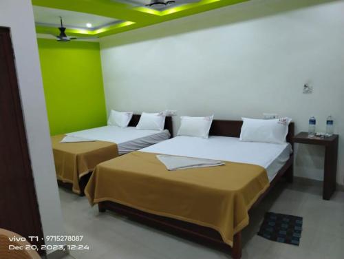two beds in a room with green walls at RR Residency in kāraikāl