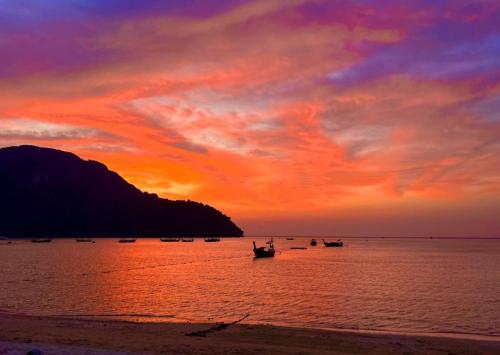 a group of boats in the water at sunset at Blanco Beach Bar Hostel in Phi Phi Don