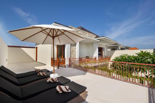 a patio with an umbrella and a couch and chairs at Daha Mansions Seminyak in Seminyak