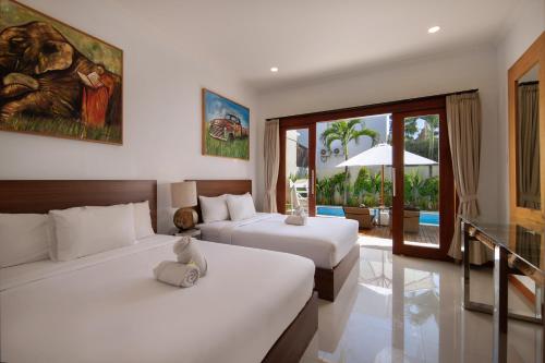 a hotel room with two beds and a balcony at Daha Mansions Seminyak in Seminyak